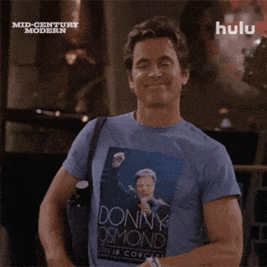a man wearing a donny osmond t-shirt is holding a purple object and says worth every penny